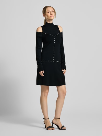 Kobiece modelka nosi czarną sukienkę mini z mieszanki wiskozy marki Minikleid aus Viskose-Mix Modell 'Abito Maglia Corto' od Liu Jo White, z długim rękawem, stójką, zdobieniem ozdobnymi kamieniami, wycięciami; dopasowany krój, widoczne proste linie i miękka faktura, widok całej sylwetki z przodu.