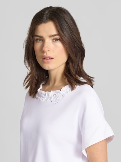 Vrouwenmodel draagt T-shirt met Eingrifftasche am Saum van Marc Cain, mix van katoen en elastaan, los model, ronde hals met tunnelkoord. Nahaufnahme bovenlichaam.