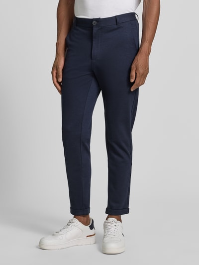 Mężczyzna nosi Slim Fit Hose mit Viskose-Anteil in verkürzter Passform von Lindbergh, granatowe, mieszanka wiskozy, krój slim fit, wpuszczane kieszenie, kieszenie z tyłu, zapięcie na guzik i zamek błyskawiczny, szerokość w rozmiarze M: 42 cm, długość wewnętrzna nogawki: 72 cm, Ganzkörperansicht z przodu.