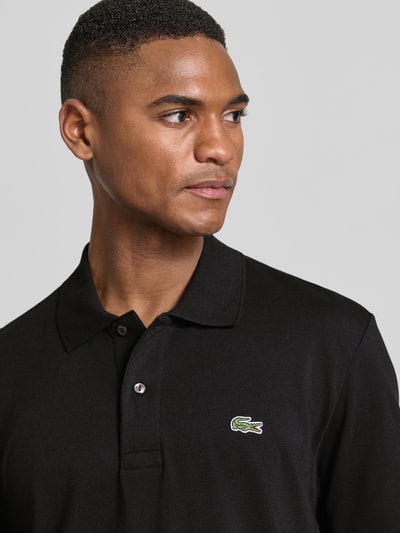 Männermodel trägt Regular Fit Poloshirt aus Baumwoll-Mix von Lacoste, Optik: Unifarben, Logo-Detail, Nahaufnahme Oberkörper.