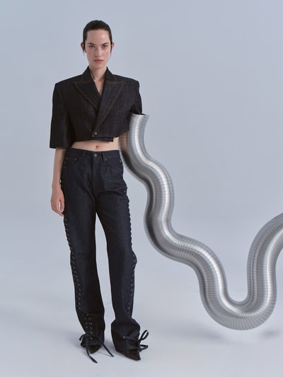Frauenmodel trägt Cropped Blazer im Denim-Look von The Mannei aus reiner Baumwolle, gerade Passform, dunkelblaue Struktur, Ganzkörperansicht von vorne.