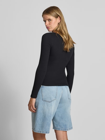 Frauenmodel trägt schwarzes Slim Fit Shirt aus Baumwoll-Mix Modell 'MAYA' von NOISY MAY, Ripp-Optik, langärmlig, kombiniert mit hellblauer Jeansshorts, Ganzkörperansicht Rückansicht.