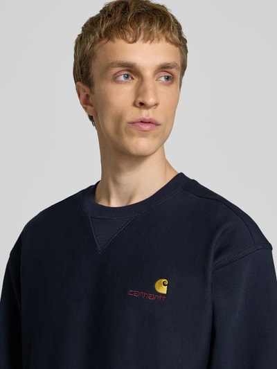 Männermodel trägt Regular Fit Sweatshirt mit Logo-Stitching von Carhartt Work In Progress aus Baumwoll-Mix, Nahaufnahme Oberkörper.