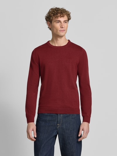 Männermodel trägt Regular Fit Pillover aus reiner Baumwolle von s.Oliver RED LABEL in Dunkelrot, kombiniert mit Jeans, Ganzkörperansicht von vorne.