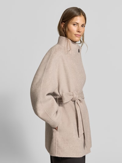 Frauenmodel trägt Mantel mit Woll-Anteil von MYON in Beige, gerader Schnitt, Stehkragen, Taillenband, Material-Mix, Ganzkörperansicht von vorne.