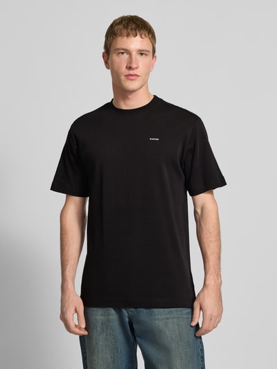 Męski model nosi Regular Fit T-Shirt mit Logo-Print Modell 'True' od G-Star Raw, czarny kolor, okrągły dekolt, długość tyłu 66 cm w rozmiarze M, Ganzkörperansicht von vorne.