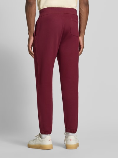 Männermodel trägt Relaxed Fit Sweathose aus Baumwoll-Mix von Polo Ralph Lauren in Dunkelrot, glatte Textur, Ganzkörperansicht Rückansicht. Herren Sweathose von Polo Ralph Lauren