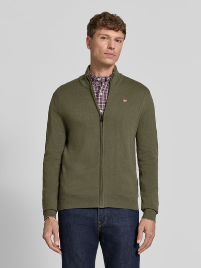 Männermodel trägt Strickjacke mit Logo-Stitching Modell 'DAMAVAND' von Napapijri aus reiner Wolle in Olivgrün, Regular Fit, Ganzkörperansicht von vorne.