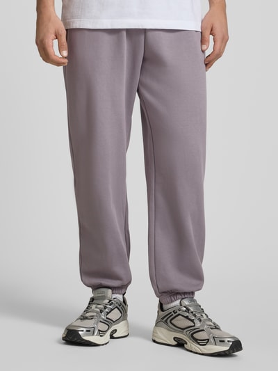 Männermodel trägt Sweatpants mit Logo-Stitching von The North Face in Grau, elastischer Bund, Baumwoll-Mix, Ganzkörperansicht von vorne.