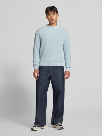 Männermodel trägt Regular Fit Strickpullover aus reiner Baumwolle von REVIEW, hellblau, Rundhalsausschnitt, Ganzkörperansicht von vorne.