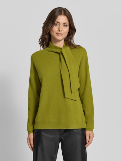 Vrouwenmodel draagt pullover van kasjmier met sjaal-detail van Christian Berg Woman in olijfgroen, recht model, opstaande kraag, ribboorden, ruglengte maat M 60 cm, mouwlengte maat M 54 cm, recht model, detailopname bovenlichaam, voorkant.