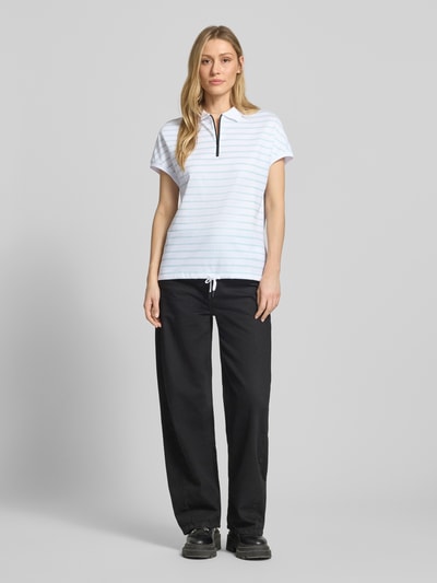 Frauenmodel trägt Regular Fit Poloshirt mit Reißverschluss von FIRE + ICE im Allover-Look, Modell GAJA2, Ganzkörperansicht von vorne.