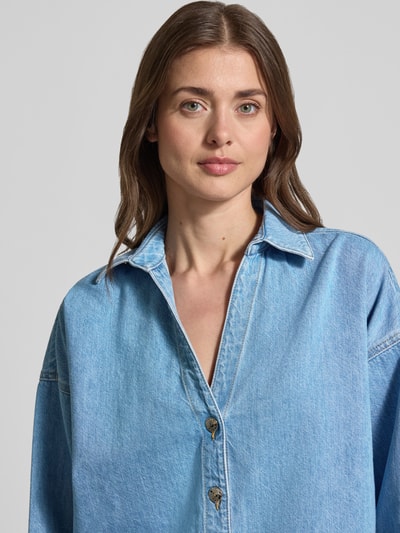 Vrouwenmodel draagt Jeansbluse mit überschnittenen Schultern van comma, lichtblauwe katoenmix, loose fit, Kentkraag, V-hals, knoopsluiting, kimonomouwen, middelste textuurcontrast, detailopname bovenlichaam.