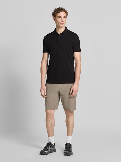 Männermodel trägt schwarzes Regular-Fit Poloshirt aus reiner Baumwolle Modell 'PIO 1' von BOSS Green, Ganzkörperansicht von vorne.