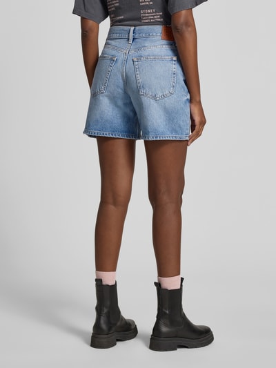 Frauenmodel trägt Regular Fit Shorts in Denim-Optik von Anine Bing aus reiner Baumwolle mit 5-Pocket-Design, Knopf-Reißverschluss, Ganzkörperansicht Rückansicht.