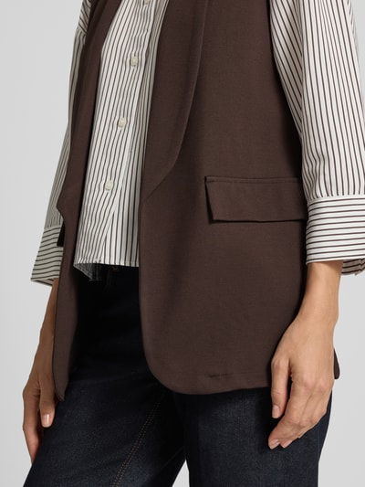 Vrouwenmodel draagt bodywarmer van viscosemix met sjaalkraag Model 'Am44br' van ZABAIONE, kleur bruin, klepzakken, straight fit, detailopname zijkant, dames bodywarmer met stretch, ruglengte maat S 70 cm, schouderbreedte 33 cm, borstwijdte 48 cm.