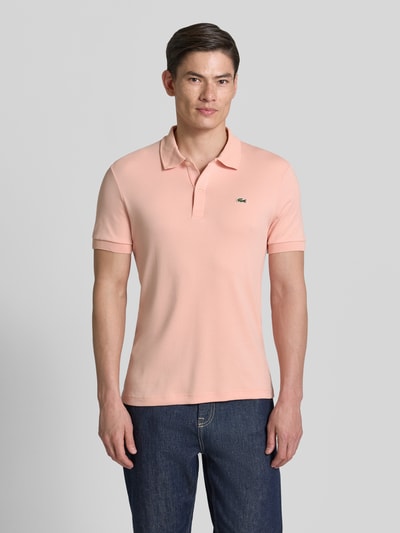Männermodel trägt Regular Fit Poloshirt aus reiner Baumwolle von Lacoste, Optik: Unifarben, Logo-Detail, Ganzkörperansicht von vorne.