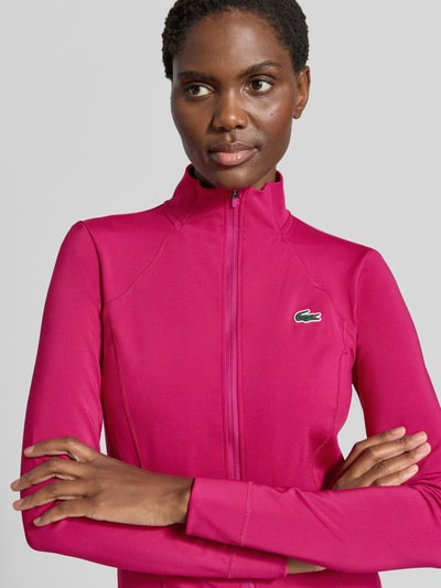 Frauenmodel trägt Slim fit Trainingsjacke mit Logo-Patch von Lacoste in kräftigem Pink, glatte Textur, Nahaufnahme Oberkörper, Damen Trainingsjacke von Lacoste Sport