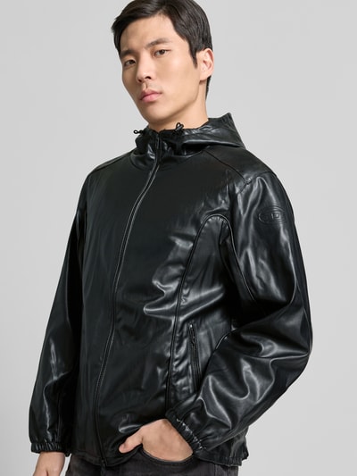 Männermodel trägt Regular Fit Jacke mit Stehkragen von Diesel in Leder-Optik, Schwarz, zweiwegereißverschluss, Ganzkörperansicht von vorne.