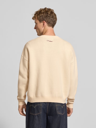 Männermodel trägt Relaxed Fit Strickpullover aus reiner Baumwolle von PROHIBITED in Beige mit gerippten Abschlüssen, Rückenansicht.