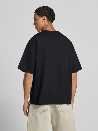 Mannenmodel draagt T-shirt met motiefprint model 'MENTON' van Jack & Jones, puur katoen, relaxed fit, ronde hals, ruglengte maat M 71 cm, geheel van achteren.