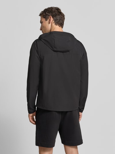 Männermodel trägt schwarze Regular Fit Trainingsjacke mit Label-Print Modell 'OW_Airynix JT HD 2' von BOSS Green, Ganzkörperansicht Rückansicht.