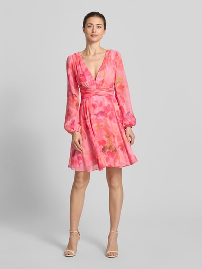 Frauenmodel trägt Cocktailkleid mit Ballonärmeln und V-Ausschnitt von Jake*s Cocktail aus Chiffon, Taillierter Schnitt, Minikleid, Blumenmuster, Rückseitiger V-Ausschnitt und Reißverschluss, Rückenlänge 91 cm, Brustweite 40 cm, Ärmellänge 65 cm, Ganzkörperansicht von vorne.