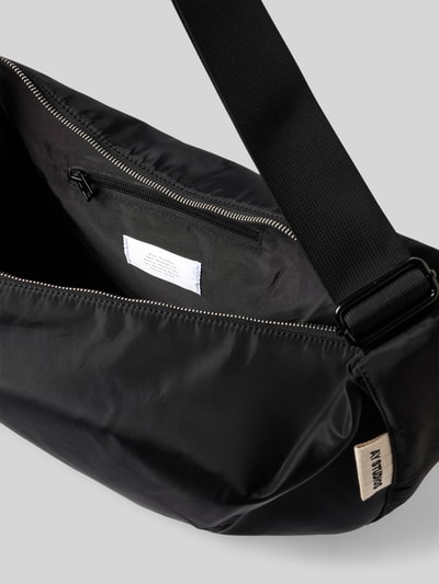 Produktfoto, schwarze Bauchtasche mit Logo-Detail von AY STUDIOS aus Nylon, sichtbares Innenfach mit Reißverschluss, glatte Textur