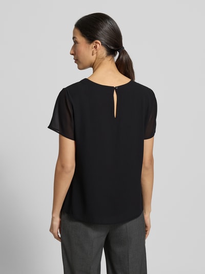 Männermodel trägt Regular Fit Blusenshirt mit semitransparenten Ärmeln von s.Oliver BLACK LABEL, czarna, jednokolorowa, krój regular fit, okrągły dekolt, krótki rękaw z szyfonu, widoczny 1-guzikowy zamek, widoczna faktura materiału, widok całej sylwetki od tyłu.