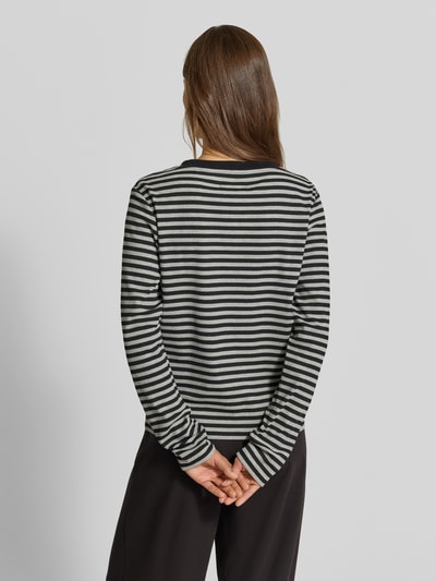 Frauenmodel trägt Longsleeve mit Henley-Kragen von MYON im Streifenmuster, Ripp-Struktur, tailliert, Ganzkörperansicht Rückansicht.