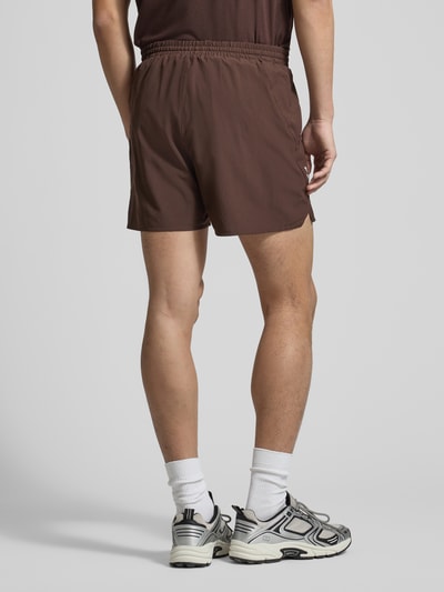 Mannenmodel draagt Shorts mit elastischem Bund und Eingrifftaschen van Salomon, regular fit, bruin, productdetails zichtbaar, volledig lichaam achteraanzicht