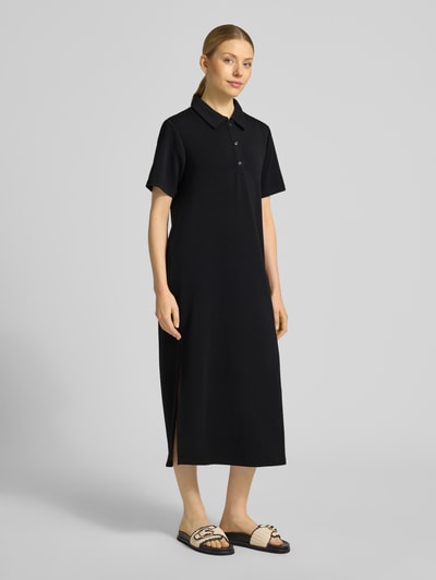 Frauenmodel trägt Polokleid mit Knopfleiste Modell 'Helle' von My Essential Wardrobe in Schwarz, Material-Mix mit Viskose, gerader Schnitt, Midikleid, Ganzkörperansicht von vorne.