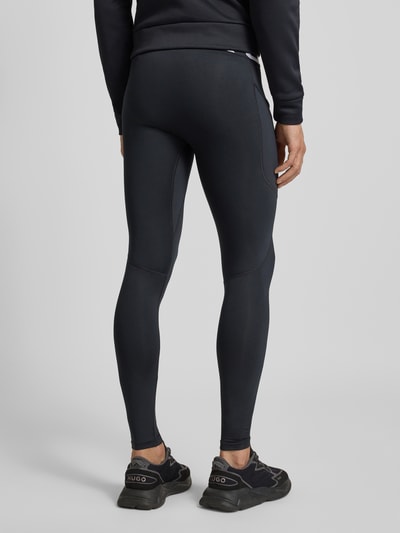 Mężczyznę nosi Legginsy z elastycznym pasem i logo od Under Armour, mieszanka materiałów z dodatkiem streczu, dopasowany krój, długość wewnętrzna nogawki 34 cm przy rozmiarze M, widok całej sylwetki z tyłu.