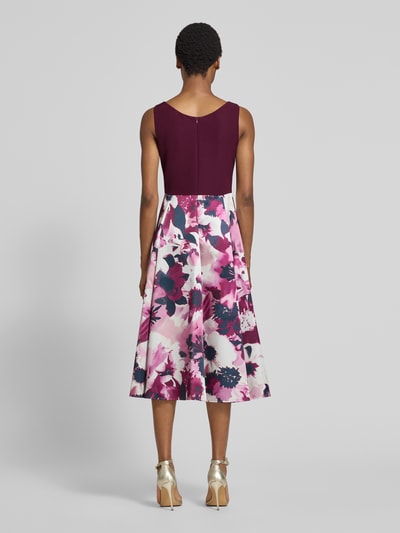 Frauenmodel trägt Tailliertes Cocktailkleid mit Allover-Muster von Vera Mont in Weinrot und Rosa mit floraler Struktur, Ganzkörperansicht Rückansicht.