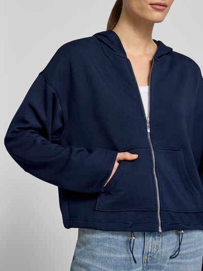 Kobieta modelka nosi Regular Fit Sweatjacke mit Kapuze od Christian Berg Woman z elastycznej mieszanki materiałów z domieszką modalu, kieszeń kangurka, pas z tunelem, ciemnoniebieski kolor, faktura gładka, zbliżenie na górną część ciała, widok z przodu.