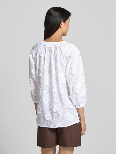 Frauenmodel trägt Regular Fit Bluse mit V-Ausschnitt und 3/4-Arm von Comma, aus Material-Mix mit Baumwoll-Anteil, Stitchings, Rückenlänge bei Größe 36: 68 cm, Ärmellänge bei Größe 36: 57 cm, lockere Form, weiße, florale Struktur, Ganzkörperansicht Rückansicht.