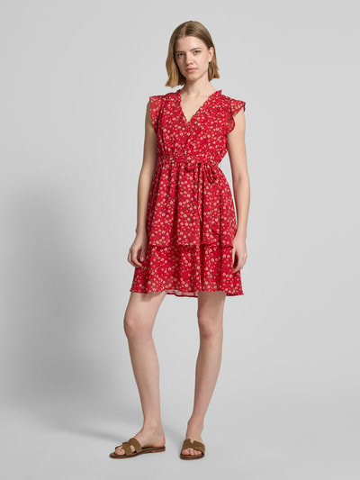 Frauenmodel trägt Minikleid mit floralem Allover-Print von Apricot in kräftigem Rot mit Rüschenbesatz, V-Ausschnitt, Taillierter Passform, abnehmbarem Taillenband, ärmelloses Design, Rückenlänge 87 cm, Brustweite 47 cm, Ganzkörperansicht von vorne.