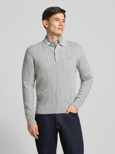 Männermodel trägt Regular Fit Strickpullover aus reiner Baumwolle von Tommy Hilfiger, Optik: Unifarben, Zopfmuster, Logo-Applikation, Polokragen, Langarm, Ärmelabschluss und Rumpfabschluss gerippt, Materialverarbeitung: Strick, Ganzkörperansicht von vorne.