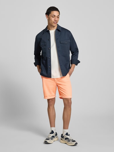 Männermodel trägt Regular Fit Shorts mit Münztasche von Superdry in Apricot, Baumwoll-Mix, Seitentaschen, Ganzkörperansicht von vorne.