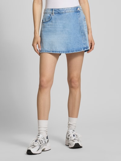 Frauenmodel trägt Jeans-Skort in hellblauer Waschung von REVIEW, Reine Baumwolle, Wickel-Optik, Eingrifftasche, Gesäßtaschen, Ganzkörperansicht von vorne.