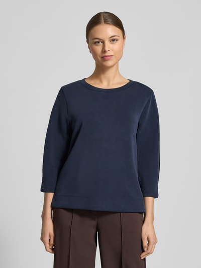 Modelka kobieca ma na sobie Comfort Fit Sweatshirt aus Modal-Mix od s.Oliver RED LABEL, granatowy kolor, krój comfort fit, dekolt okrągły, rękaw 3/4, boczne rozporki, materiał scuba, widok całej sylwetki z przodu.
