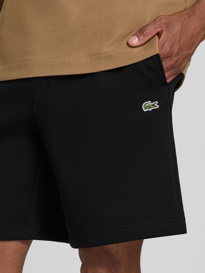 Männermodel trägt Regular Fit Sweatshorts aus Baumwoll-Mix von Lacoste in Schwarz, glatte Struktur, Herren Sweatshorts von Lacoste, Nahaufnahme Oberkörper