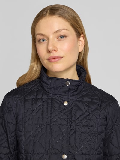 Frauenmodel trägt Steppjacke mit Stehkragen und Eingrifftaschen von Fuchs Schmitt, dunkelblau, strukturierte Oberfläche, Nahaufnahme Oberkörper. Regular Fit, Knopfleiste, 64 cm Rückenlänge, 43 cm Schulterbreite, 49 cm Brustweite, 65 cm Ärmellänge.