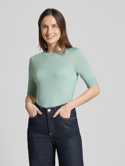 Modelka nosi Slim Fit Pullover aus reiner Schurwolle Modell 'FARBELLA' von BOSS, miękki, jednolity, jasny zielony, krój slim fit, półrękaw, okrągły dekolt, drobny splot, czysta wełna, widok całej sylwetki z przodu.