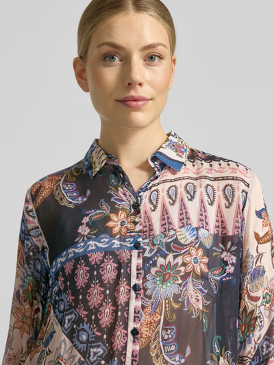 Frauenmodel trägt Regular Fit Hemdbluse aus reiner Viskose von Milano Italy mit farbenfrohem Blumenmuster, Nahaufnahme Oberkörper. Hemdblusenkragen, durchgängige Knopfleiste, langärmelig, Rückenlänge 61 cm, Ärmellänge 61 cm.