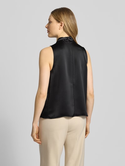 Vrouwenmodel draagt Regular Fit Blusentop in Wickel-Look model 'CHELINA-1' van HUGO, look: effen, satijn materiaalverwerking, laagjeslook, labelapplicatie, mouwloos, mock neck kraagmodel, wikkellook, sluiting verborgen, kleur zwart, gladde textuur. Ganzkörperansicht achteraan.