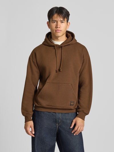 Männermodel trägt Regular Fit Hoodie aus Baumwoll-Mix von Levi's® in Braun, lockere Passform, glatte Textur, Ganzkörperansicht von vorne.