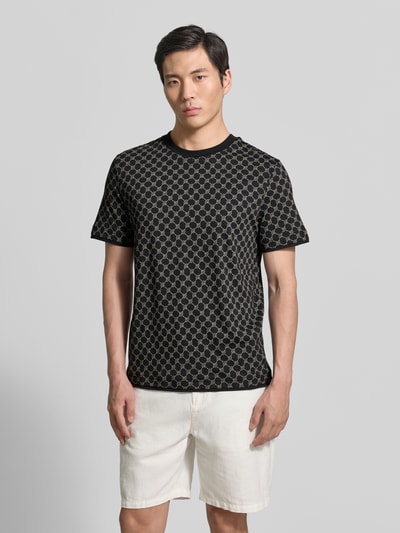 Männermodel trägt T-Shirt mit Logo-Muster und Rundhalsausschnitt von JOOP! Collection, Baumwoll-Lyocell-Mix, Regular-Fit, Schwarz-Beige, Ganzkörperansicht von vorne. Rückenlänge bei Größe M: 69 cm.