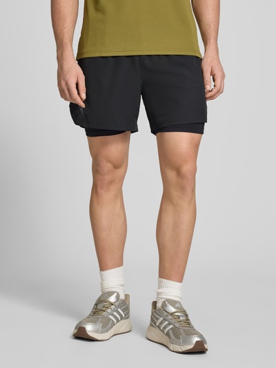 Männermodel trägt Shorts im 2-in-1-Look von HALO in Schwarz, Regular Fit, elastischer Bund, Material-Mix mit Stretch, Nahaufnahme Oberschenkel.