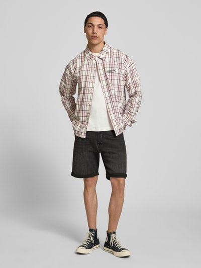 Männermodel trägt Jeansshorts mit Umschlag Modell 'RICK' von Jack & Jones aus Baumwoll-Mix mit Stretch-Anteil, Regular-Fit, Ganzkörperansicht von vorne.